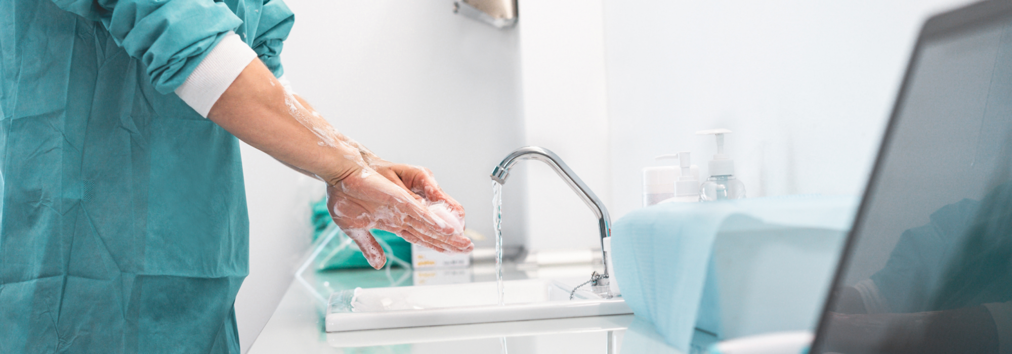 NHS staff washing hands next to laptop